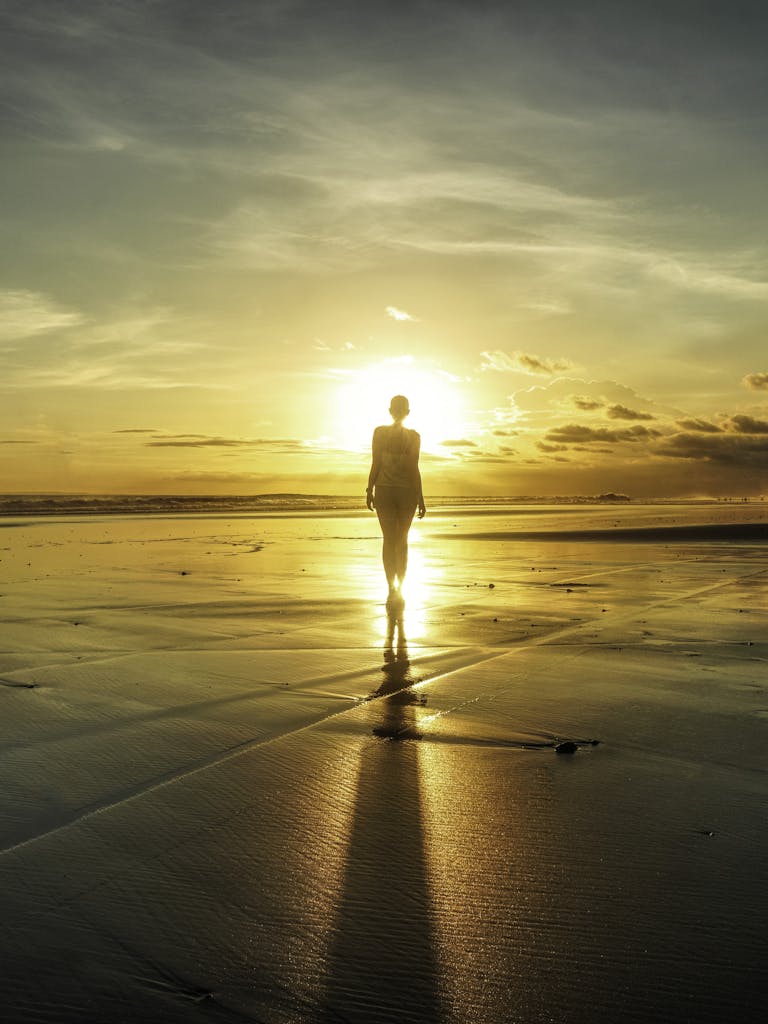 A lone silhouette on a Bali beach at sunset, creating a dramatic scene with vibrant colors.