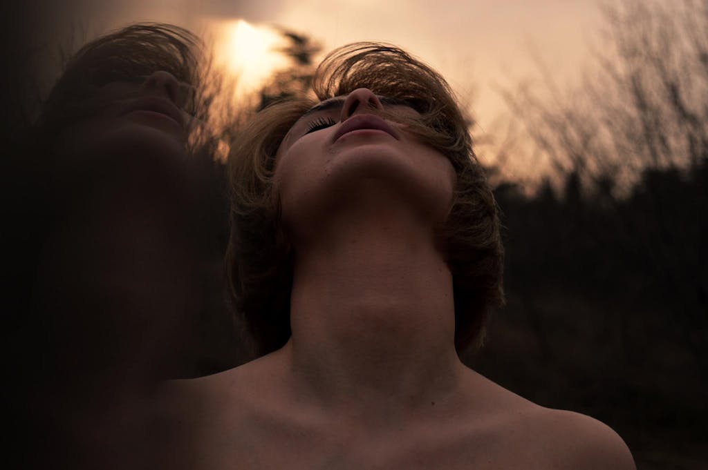 Moody portrait of a woman in nature reflecting emotion at dusk.